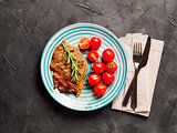 Fried steak and vegetables on blue plate, copy space