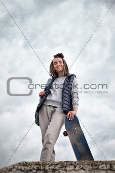 Beautiful hipster girl with skate board standing with smile