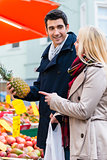 Couple buying groceries on farmers market stand