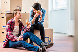 Young couple looking tired while eating a sandwich during break