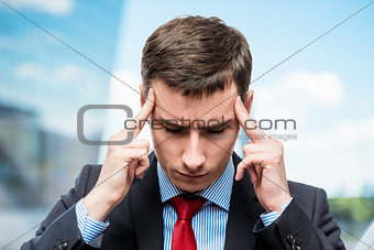 Portrait of a businessman with a strong headache and troubles in