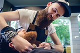 Bearded young man ready for shaving in the hair salon of a skill