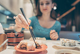 Woman eating sushi food in Japanese restaurant