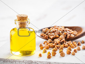 Brown buckwheat in spoon and buckwheat oil close up