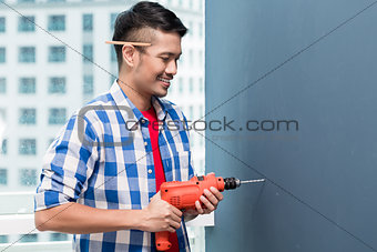 Asian do-it-yourself handyman drilling