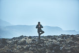 Woman hiker stands in yoga pose on volcanic Lava fields on background of mountains of Iceland.