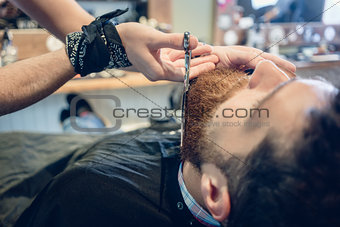 Close-up of the hand of a barber using scissors while trimming t