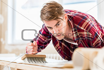 Young man applying paste to the surface of a wallpaper sheet dur