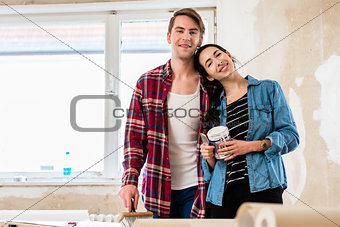 Portrait of a happy young couple holding tools for home remodeli