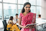 Indian business woman looking at camera while holding a tablet