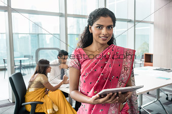 Indian business woman looking at camera while holding a tablet