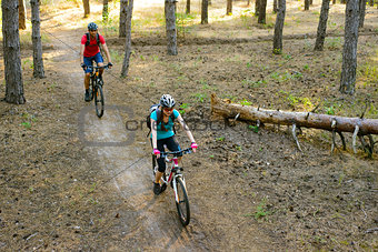 Young Couple Riding the Mountain Bikes in the Pine Forest. Adventure and Family Travel Concept.