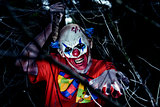 scary evil clown wielding a knife in the woods