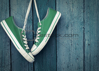 Green youth sneakers hanging on a nail
