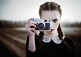 Lovely sad young girl photographing on vintage film camera. Closeup outdoor portrait