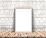 3D blank silver picture frame on a wooden table leaning against 