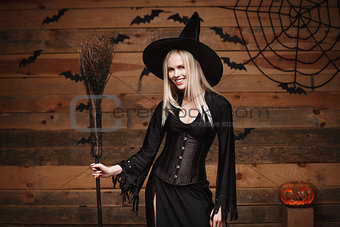 Halloween witch concept - Happy Halloween Sexy Witch holding posing over old wooden studio background.