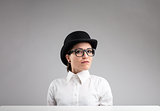 serious woman in bowler, glasses and white shirt