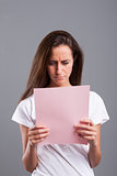 woman reads bad news on a pink sheet