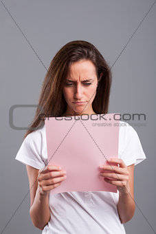 woman reads bad news on a pink sheet