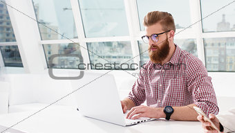 Hipster businessman at the office working with a laptop with his team