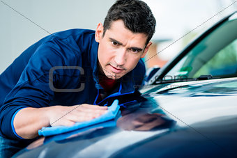 Man using an absorbent towel for drying the surface of a car