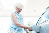 Active senior woman smiling while filling up the gas tank of her