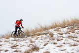 Cyclist in Red Riding Mountain Bike on the Snowy Trail. Extreme Winter Sport and Enduro Biking Concept.
