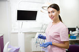 Happy young female dentist over medical office background