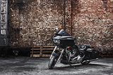 Modern black motorcycle stands against a brick wall