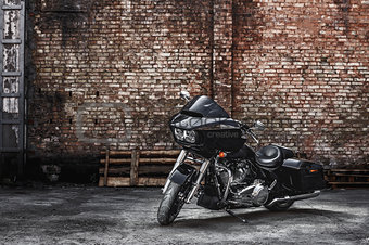 Modern black motorcycle stands against a brick wall