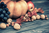 Pumpkin, apple, nuts, leaves on wooden background