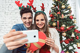 Couple making selfie photos with phone on Christmas