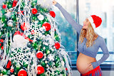 Pregnant woman adorns Christmas tree
