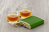 Green hip flask and glasses of whisky