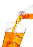 Pouring orange energy drink from bottle to glass