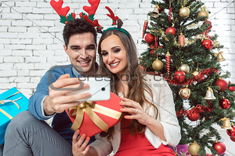 Couple making selfie photos with phone on Christmas