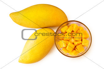 Two mango fruits and mango cubes on a plate.