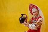 Russian woman in a folk russian dress holds a jug