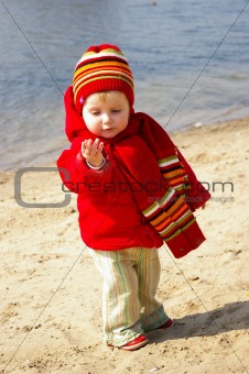 Girl plays with sand on coast of lake