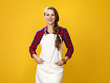 happy young woman farmer wearing apron isolated on yellow