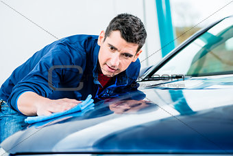 Man using an absorbent towel for drying the surface of a car