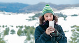 Happy woman using phone in the mountains