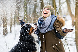 Woman walking her dog in the winter and both explore the snow to