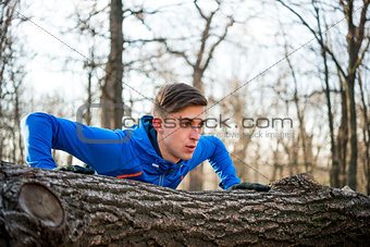 Male Runner Doing Push Up on the Log in the Park in Sunny Autumn Morning. Healthy Lifestyle and Sport Concept.
