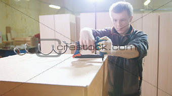 Carpenter working with an electric industrial stapler on the factory, fixing furniture details, close-up