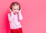 Little girl in headphones over rose background