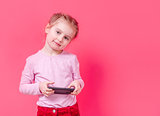 Adorable girl using smartphone over pink background
