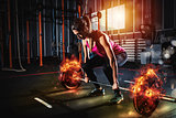 Athletic girl works out at the gym with a fiery barbell