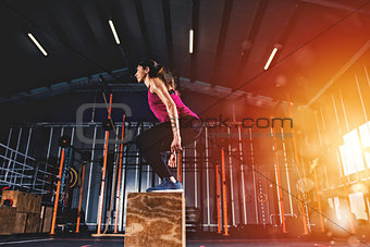 Athletic girl does box jump exercises at the gym